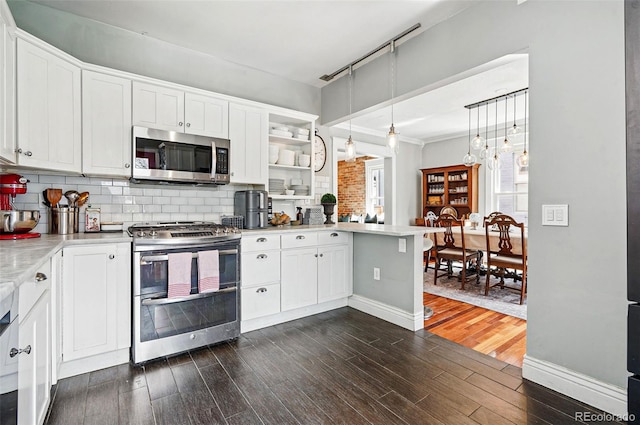 kitchen with white cabinets, appliances with stainless steel finishes, light countertops, a peninsula, and dark wood-type flooring