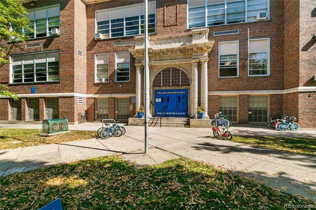 view of exterior entry featuring an attached garage, cooling unit, and brick siding
