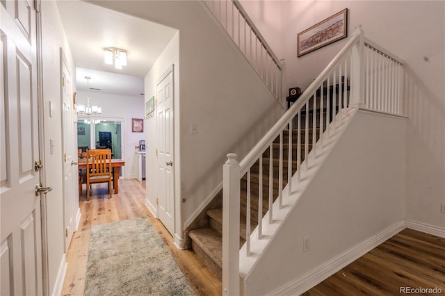 stairway featuring hardwood / wood-style flooring and a chandelier