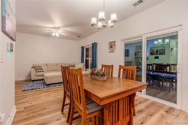 dining room with ceiling fan with notable chandelier and light wood-type flooring