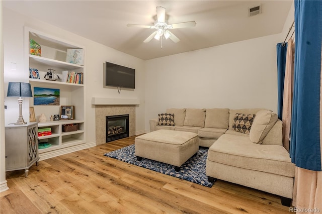 living room with hardwood / wood-style floors, ceiling fan, and a tile fireplace