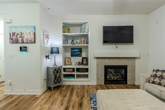 living room with hardwood / wood-style flooring and a tiled fireplace