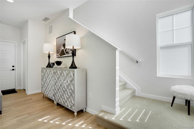 stairs with visible vents, baseboards, and wood finished floors