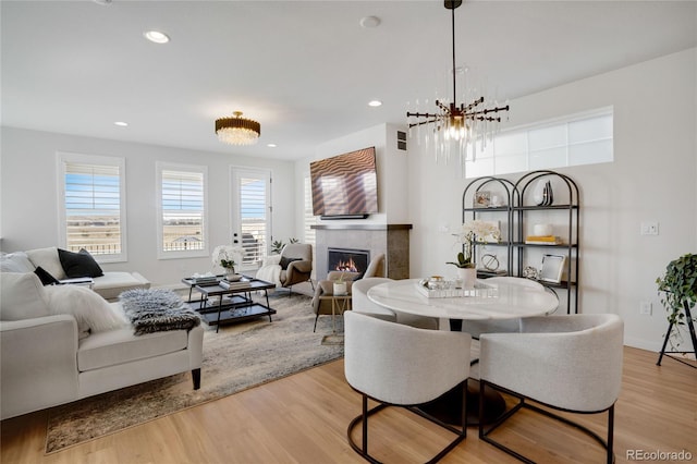 dining area featuring light wood-type flooring, recessed lighting, baseboards, and a tile fireplace