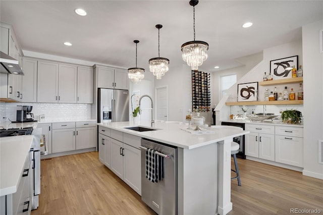 kitchen with a sink, light countertops, light wood-type flooring, tasteful backsplash, and high end appliances