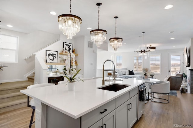 kitchen with open floor plan, light countertops, light wood-type flooring, a sink, and recessed lighting