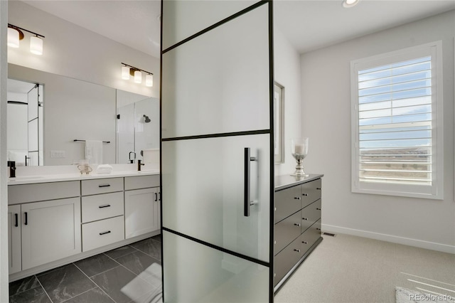 bathroom with marble finish floor, double vanity, a stall shower, a sink, and baseboards