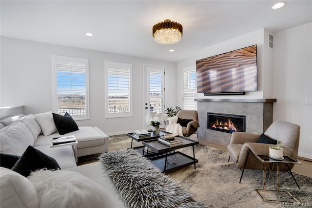 living room with a tiled fireplace, baseboards, recessed lighting, and wood finished floors