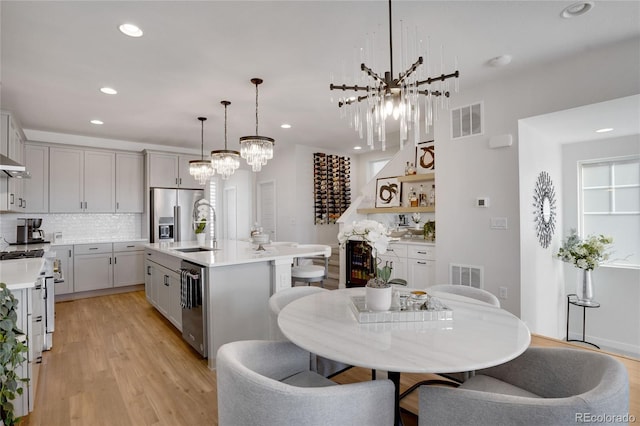 kitchen featuring an inviting chandelier, light wood-style flooring, a sink, and visible vents
