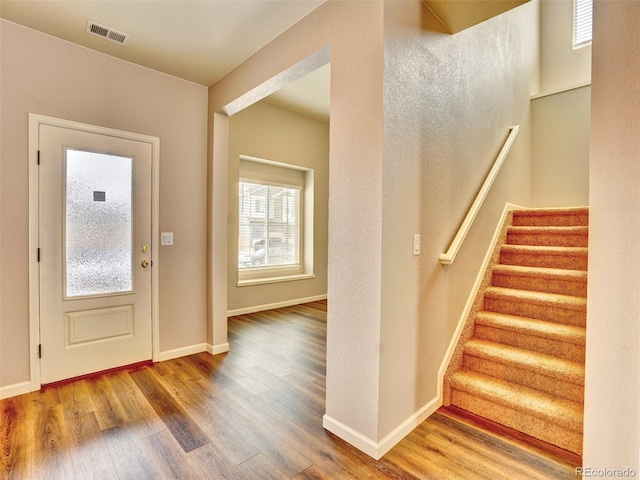 entryway with visible vents, stairway, baseboards, and wood finished floors