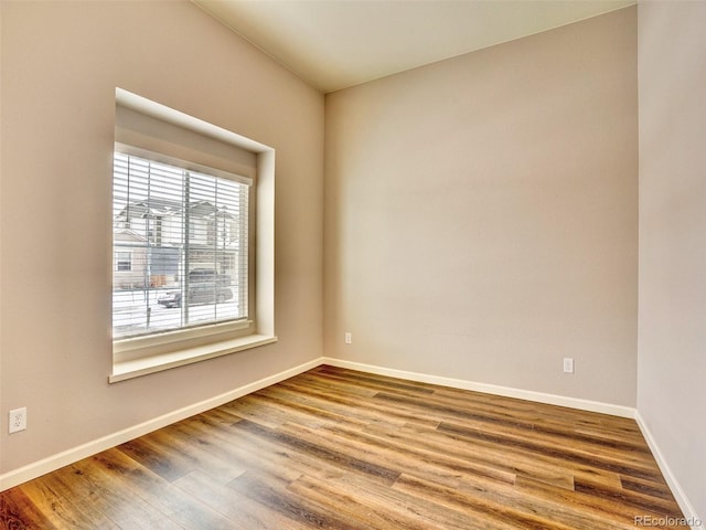 spare room featuring baseboards and wood finished floors