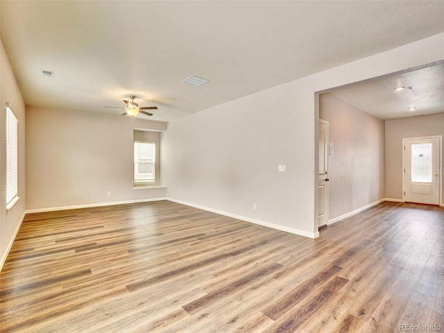 spare room with visible vents, baseboards, wood finished floors, and a ceiling fan