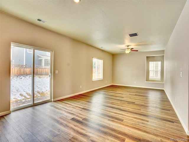 spare room featuring a ceiling fan, wood finished floors, visible vents, and baseboards