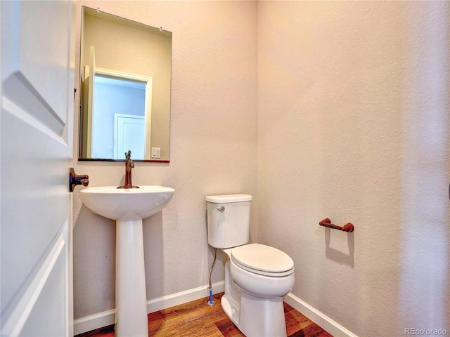 bathroom featuring toilet, baseboards, and wood finished floors