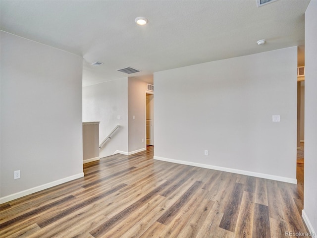 empty room with visible vents, baseboards, and wood finished floors