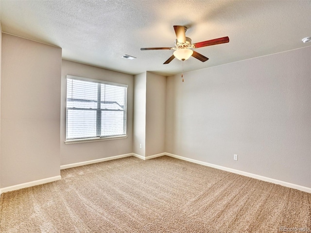 carpeted spare room featuring visible vents, a textured ceiling, baseboards, and ceiling fan