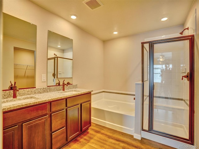 bathroom with a shower stall, a garden tub, visible vents, and a sink