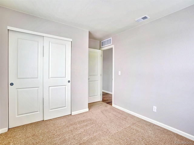 unfurnished bedroom with light colored carpet, visible vents, a closet, and baseboards