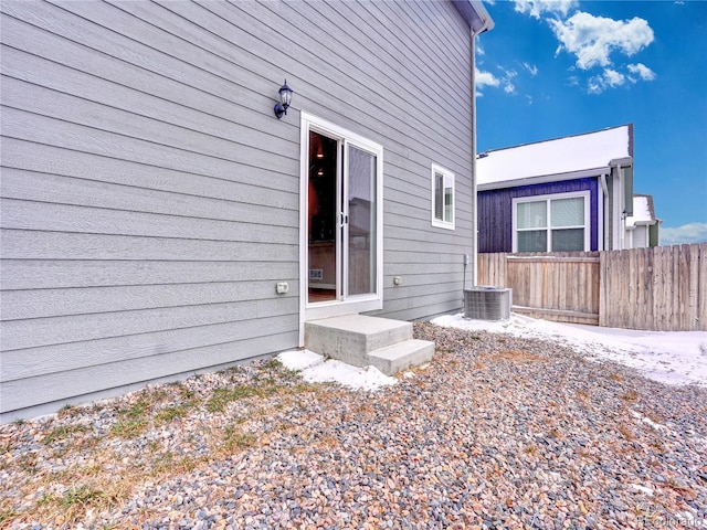 back of property featuring entry steps, central AC unit, and fence