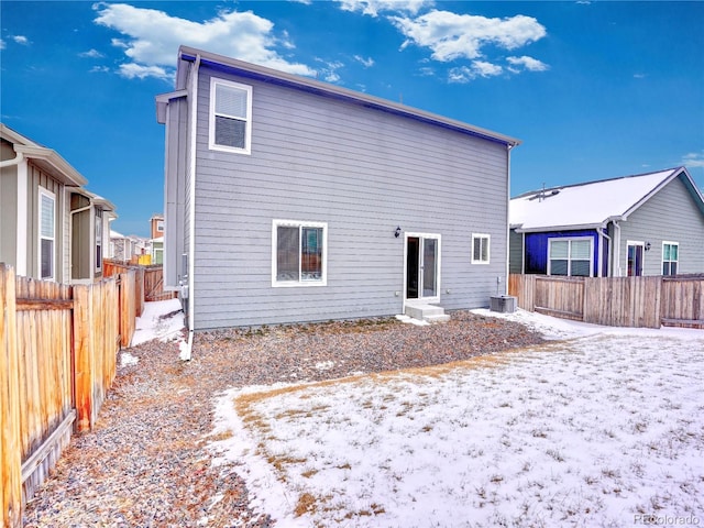 snow covered rear of property with cooling unit, entry steps, and a fenced backyard