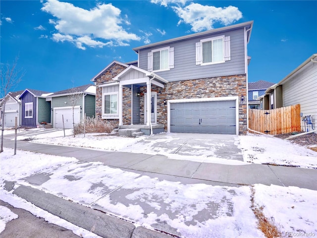 view of front of house featuring a garage, stone siding, driveway, and fence