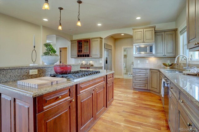 14993 W 55th Dr, Golden, CO 80403 - kitchen featuring arched walkways, built in appliances, light wood-type flooring, light stone counters, and recessed lighting