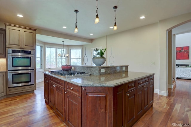 14993 W 55th Dr, Golden, CO 80403 - kitchen featuring appliances with stainless steel finishes, light wood-style floors, baseboards, recessed lighting, and arched walkways