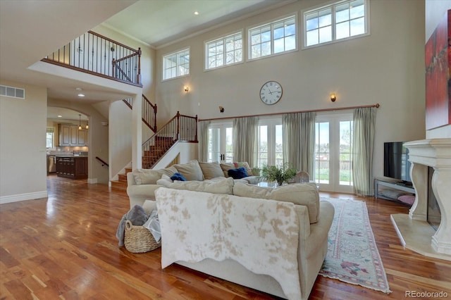 14993 W 55th Dr, Golden, CO 80403 - living room featuring a towering ceiling, stairway, healthy amount of natural light, ornamental molding, and wood finished floors