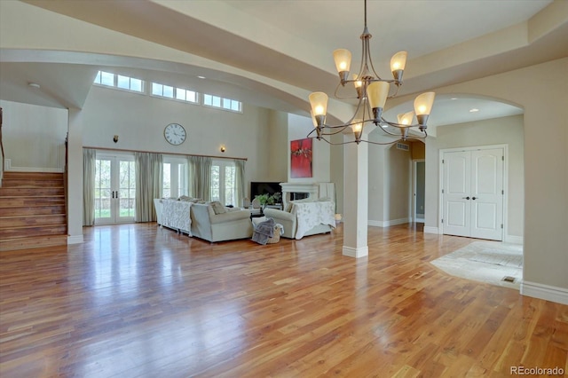 14993 W 55th Dr, Golden, CO 80403 - living room featuring arched walkways, a chandelier, light wood-type flooring, baseboards, and a high ceiling