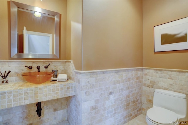 14993 W 55th Dr, Golden, CO 80403 - bathroom featuring a sink, toilet, wainscoting, and tile walls