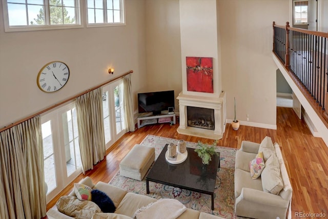 14993 W 55th Dr, Golden, CO 80403 - living room featuring wood finished floors, a fireplace with raised hearth, a high ceiling, and baseboards