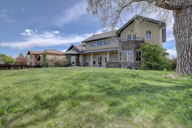 14993 W 55th Dr, Golden, CO 80403 - view of front of house featuring stone siding, a balcony, stucco siding, and a front lawn