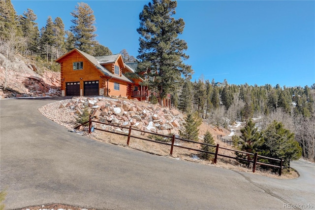 11450 Marks Dr, Conifer, CO 80433 - view of side of property with asphalt driveway, log exterior, an attached garage, and a wooded view