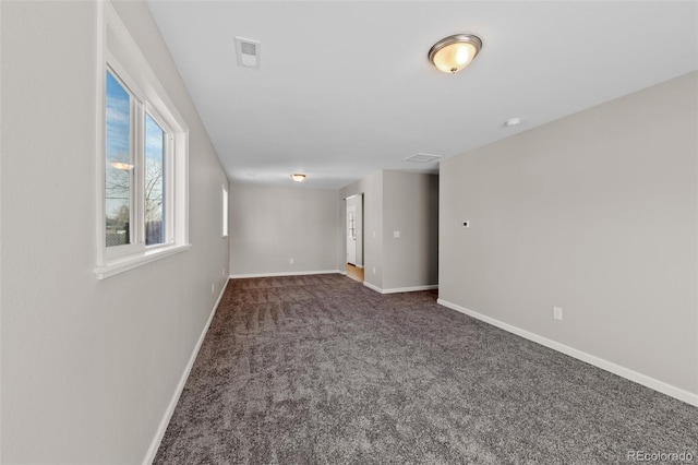 unfurnished room with dark carpet, visible vents, and baseboards