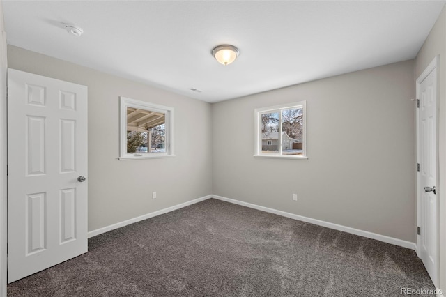 unfurnished bedroom with dark colored carpet, visible vents, and baseboards