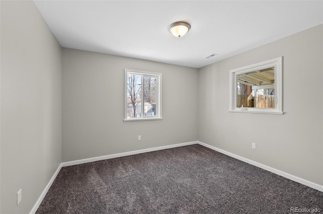 spare room featuring carpet floors, visible vents, and baseboards