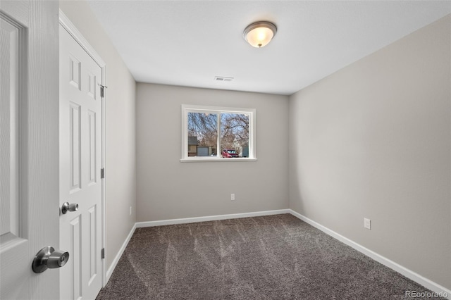 unfurnished room featuring dark colored carpet, visible vents, and baseboards