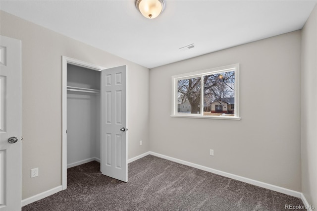 unfurnished bedroom featuring dark colored carpet, a closet, visible vents, and baseboards