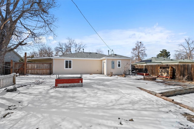 snow covered house featuring fence and a fire pit