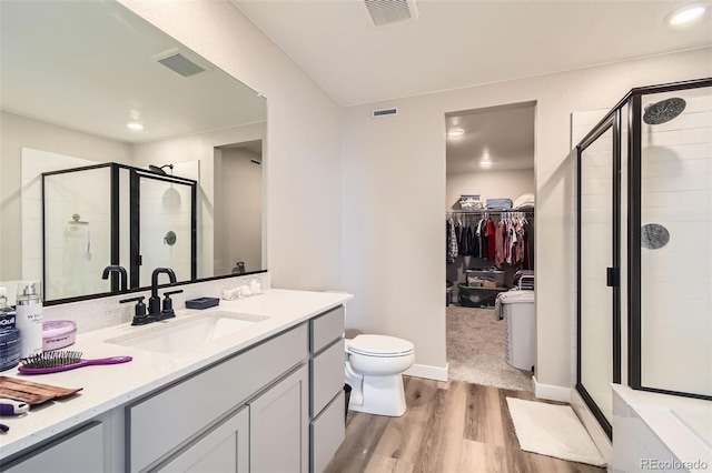 bathroom with toilet, vanity, wood-type flooring, and a shower with door