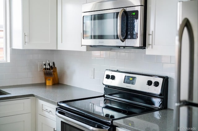 kitchen with stainless steel appliances, white cabinets, and backsplash