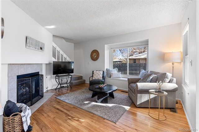 living room with a textured ceiling, light hardwood / wood-style floors, and a fireplace