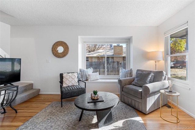 living room with a textured ceiling, light hardwood / wood-style flooring, and a healthy amount of sunlight