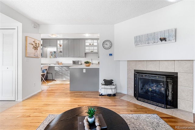 living room with a tiled fireplace, light hardwood / wood-style flooring, and a textured ceiling