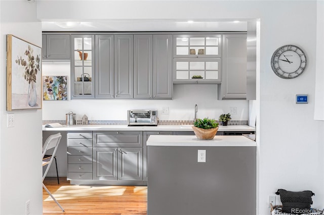 bar with gray cabinetry, sink, and light wood-type flooring