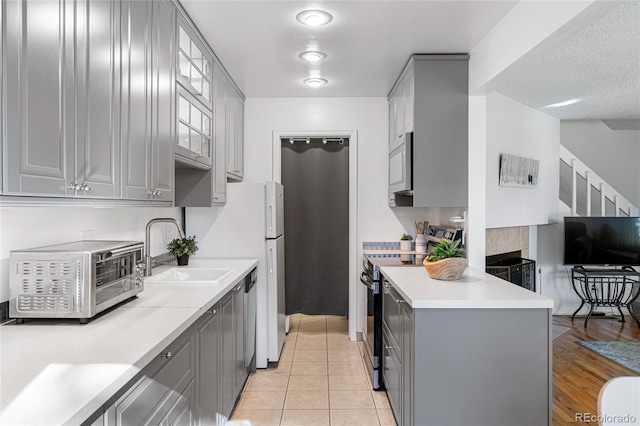 kitchen with light hardwood / wood-style flooring, stainless steel appliances, gray cabinets, and sink