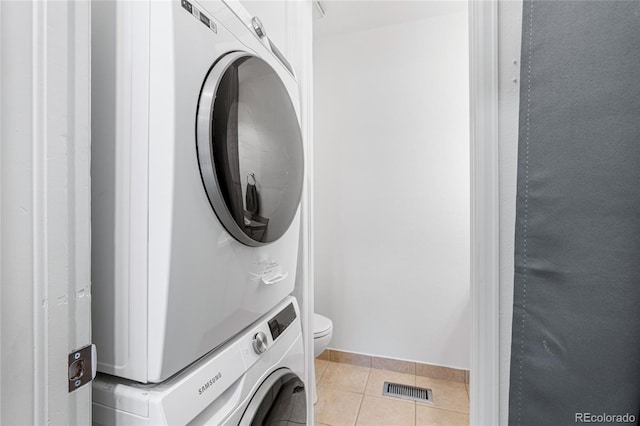 clothes washing area featuring light tile patterned floors and stacked washer / drying machine