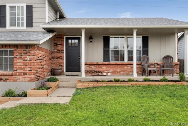 11021 Otis St, Westminster, CO 80020 - view of exterior entry with covered porch, brick siding, a lawn, and a shingled roof