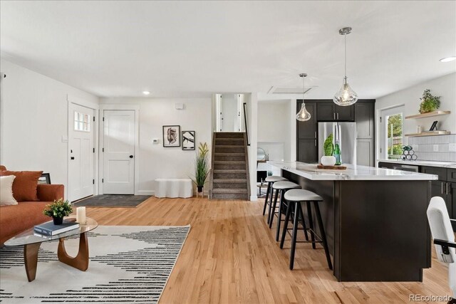 11021 Otis St, Westminster, CO 80020 - kitchen with freestanding refrigerator, light countertops, open shelves, a breakfast bar area, and a center island