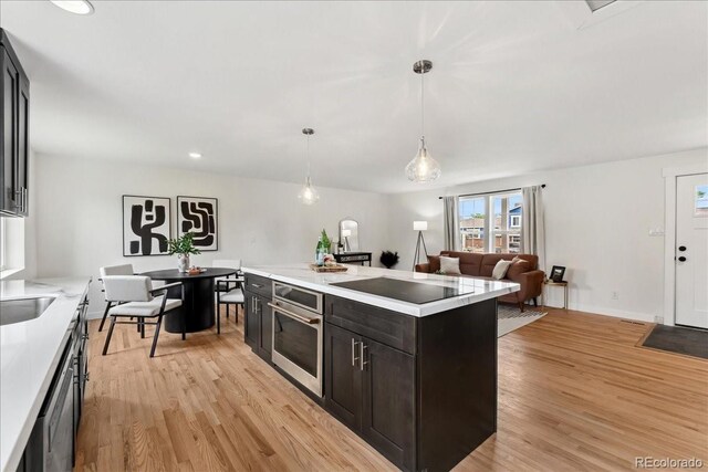 11021 Otis St, Westminster, CO 80020 - kitchen with stainless steel oven, light countertops, light wood-type flooring, black electric cooktop, and recessed lighting